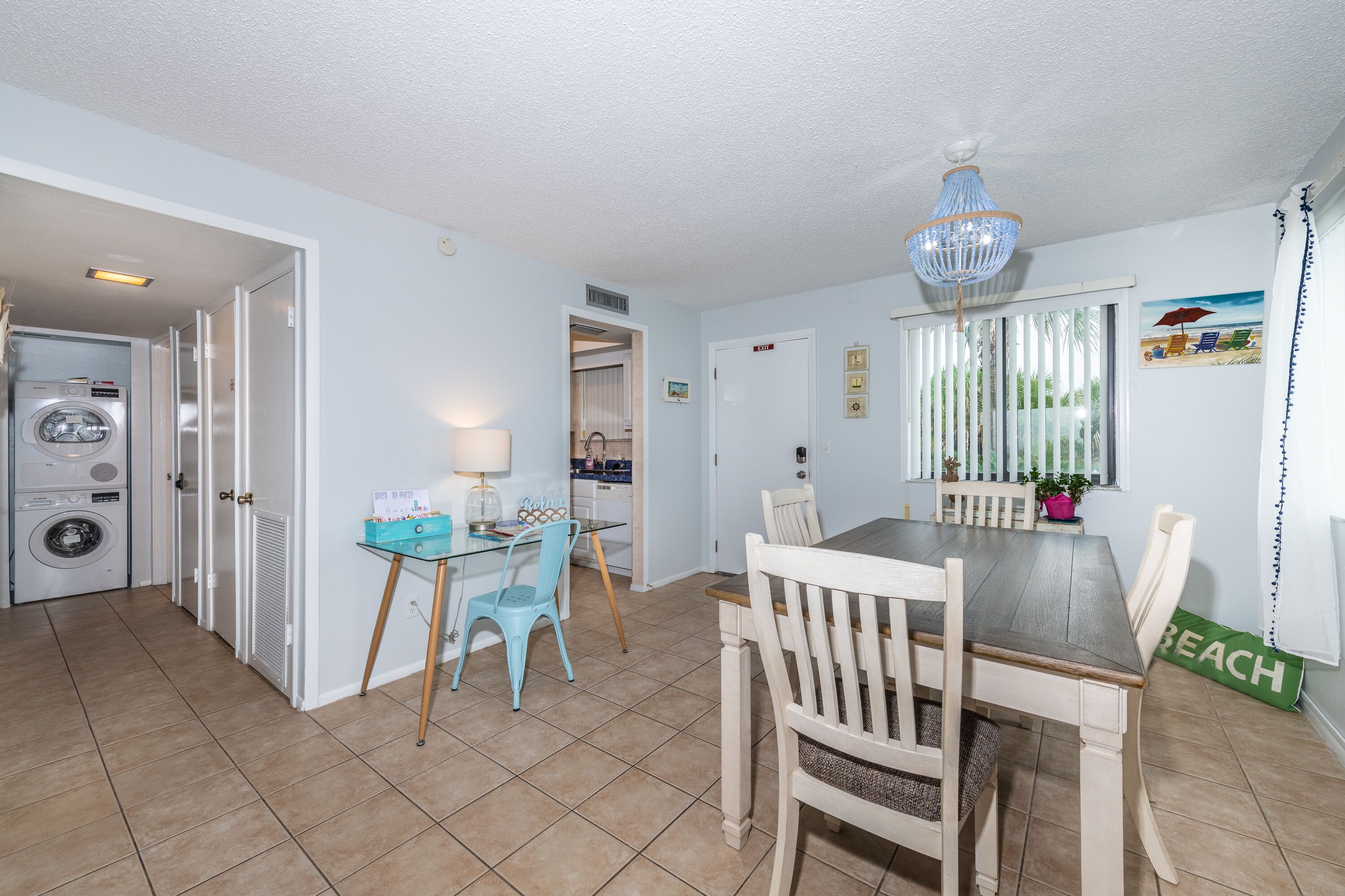 A compact kitchen with a dining area, a washing machine, and a chandelier.