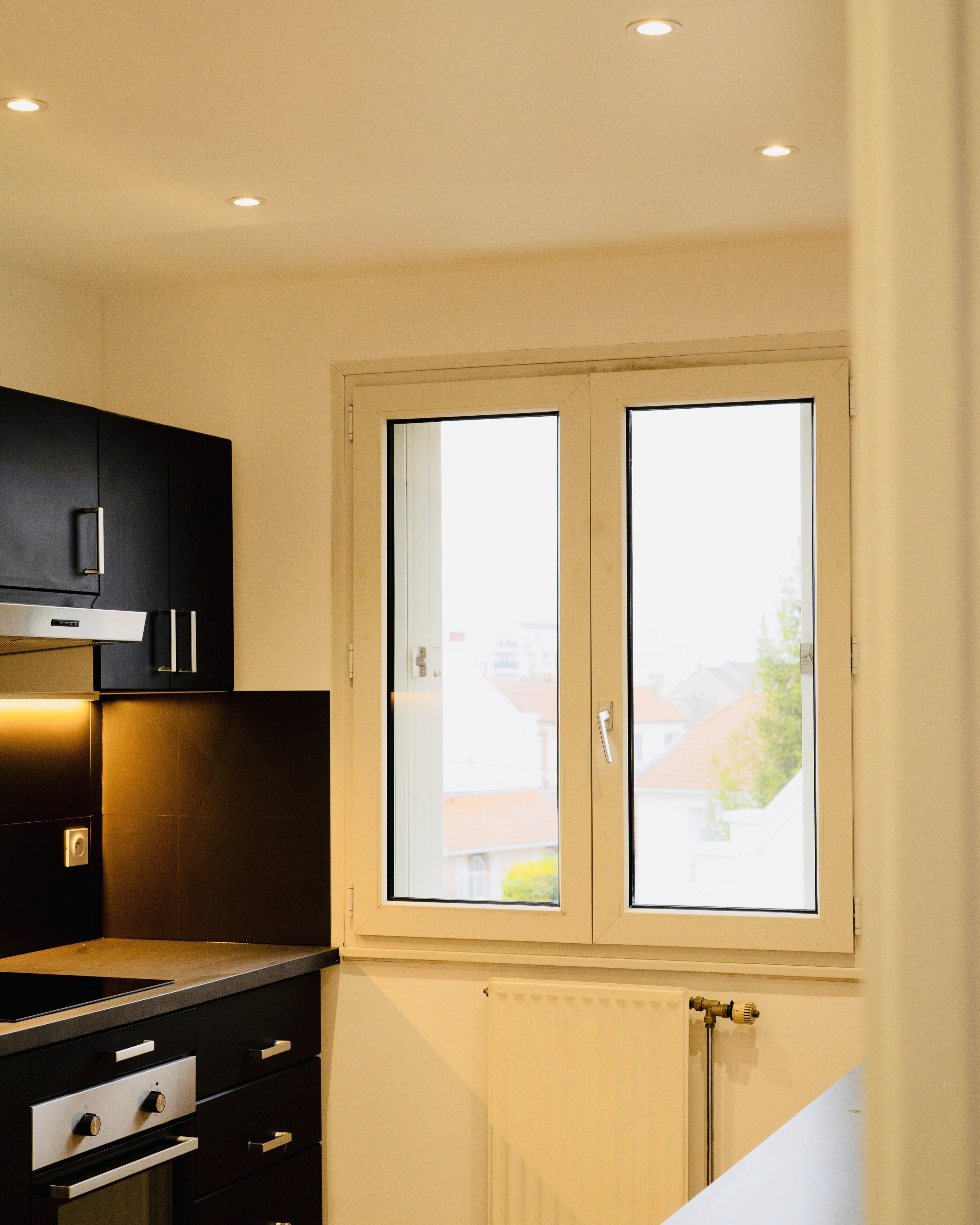 A modern kitchen with a window, built-in cabinets, and a built-in oven.