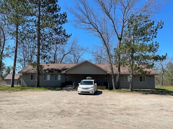 A two-story house with a garage, a car parked in front, and a clear blue sky. - Vacation Lodge for Big Groups: 8BR/8BTH, Sleeps 36, Pool Table, Vball, Fire Pit (Indian River)