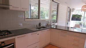 A modern kitchen with white cabinets, a stainless steel sink, and a built-in oven.