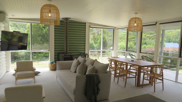 A spacious living area with a sofa, chairs, a dining table, and a fireplace.