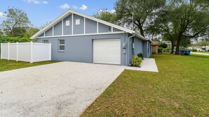 A single-story building with a garage, a gravel driveway, and a well-maintained lawn. - Entire House close to everything. (Seffner)