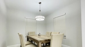 A dining area with a wooden table and four chairs, a pendant light, and a window with blinds. - Entire House close to everything. (Seffner)