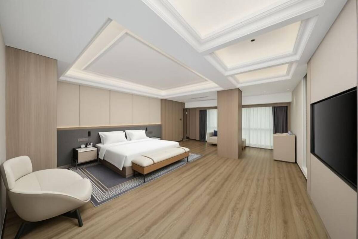 A modern hotel room with a large bed, a seating area, and a TV.