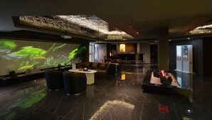 A modern lobby with a large digital screen displaying a nature scene, plush seating, and a reception area. - Lijing Peninsula Hotels (Lufeng)