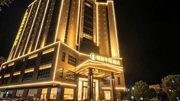 A hotel with a prominent entrance, multiple floors, and illuminated signage.