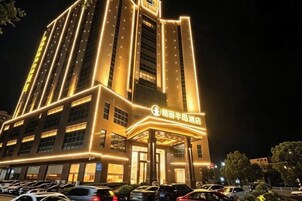 Un hotel con una entrada destacada, varios pisos y señalización iluminada.
