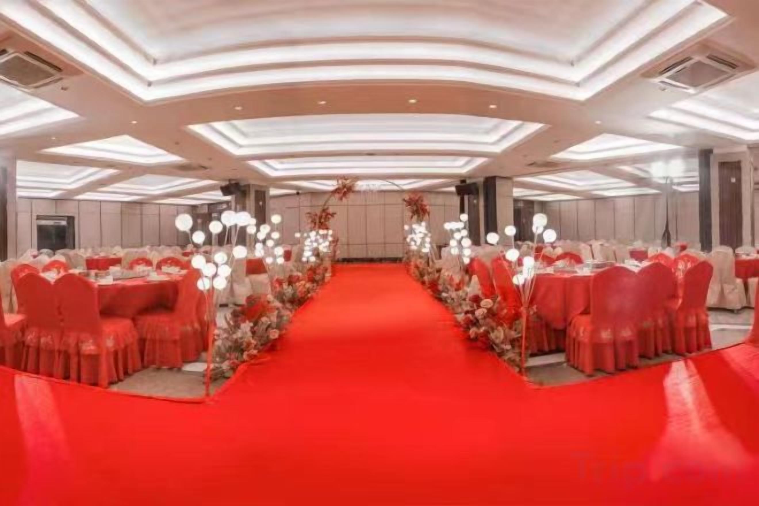 Un salón de banquetes con alfombra roja, mesas redondas y sillas.