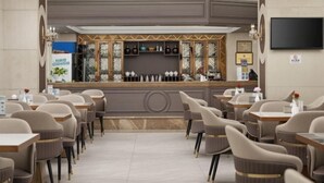 A hotel lobby with a reception desk, seating area, and a television mounted on the wall. - Lijing Peninsula Hotels (Lufeng)