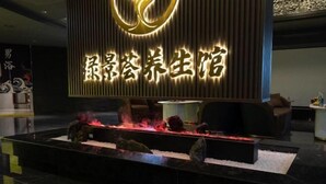A modern hotel lobby with a large illuminated sign, a reception desk, and a decorative fire feature. - Lijing Peninsula Hotels (Lufeng)