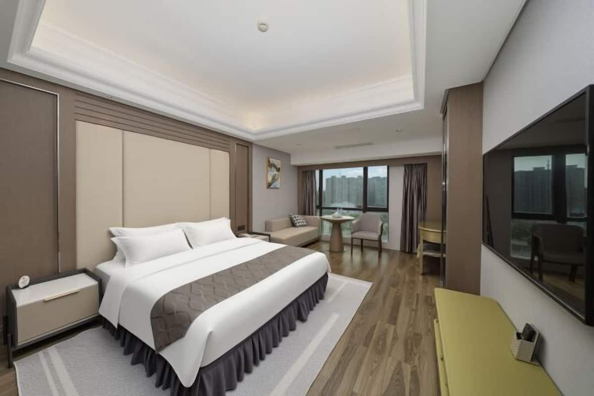 A modern hotel room with a large bed, a sofa, a small table, and a TV.