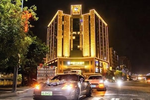 Un edificio bien iluminado con un cartel llamativo en la parte superior, una entrada espaciosa y una calle con vehículos a la vista.