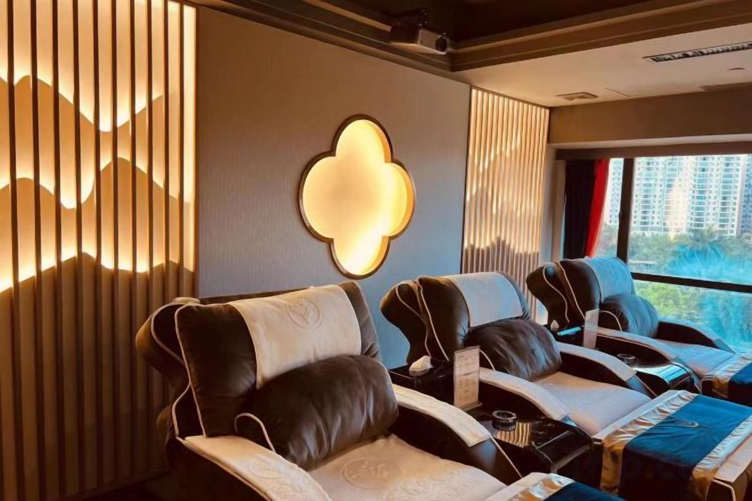 A massage room with reclining chairs, a massage table, and a large window with a view.