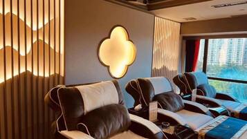 A massage room with reclining chairs, a massage table, and a large window with a view.