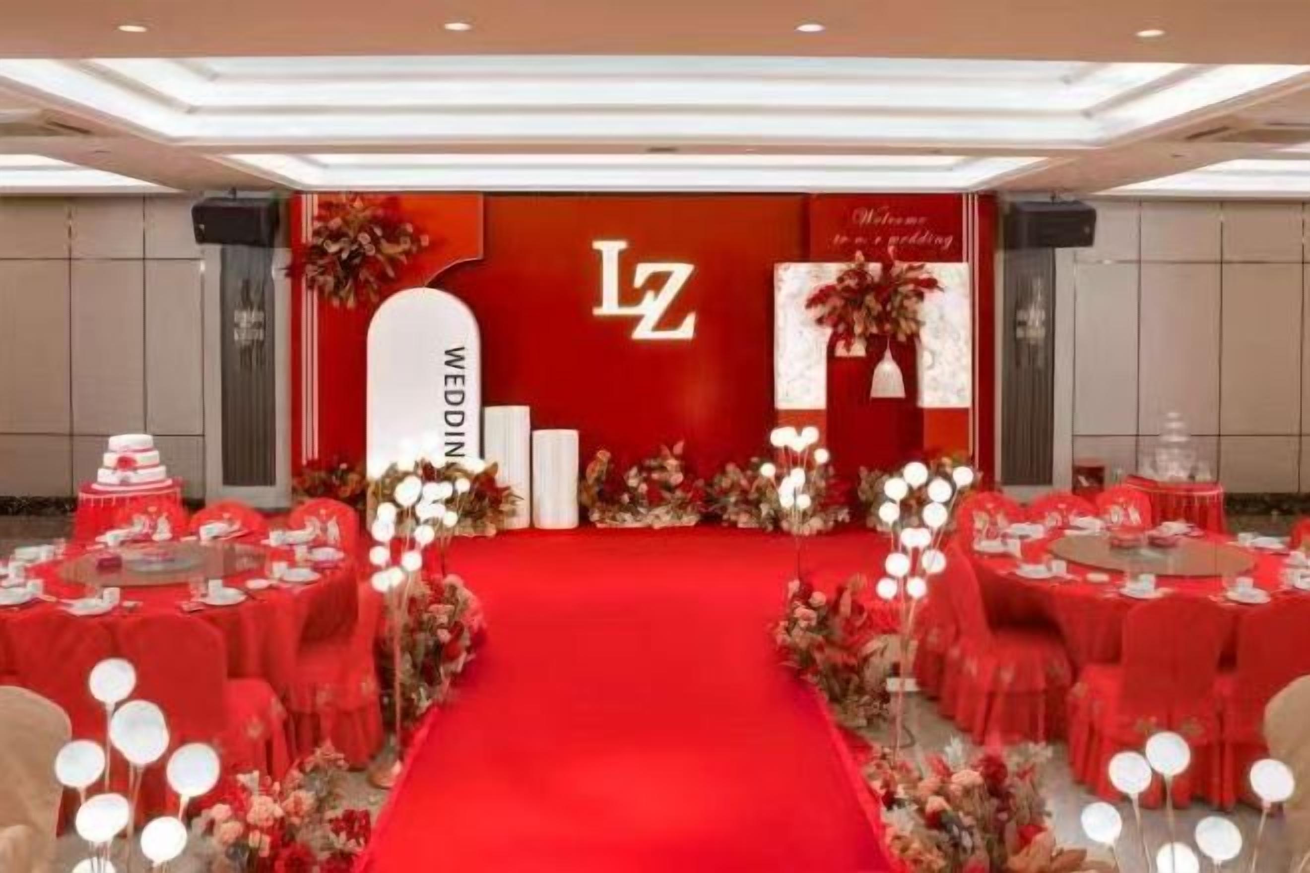 Un salón de banquetes con alfombra roja, mesas redondas y sillas dispuestas para un evento formal.