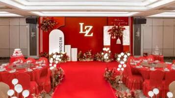 Un salón de banquetes con alfombra roja, mesas redondas y sillas dispuestas para un evento formal.