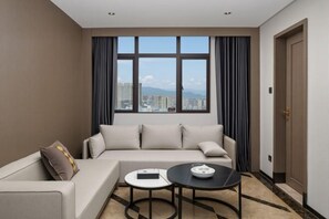 A modern hotel room with a sofa, a small round table, and a large window with curtains. - Lijing Peninsula Hotels (Lufeng)
