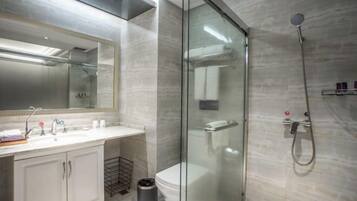 A modern bathroom with a glass-enclosed shower, a white sink with a mirror, and a toilet.