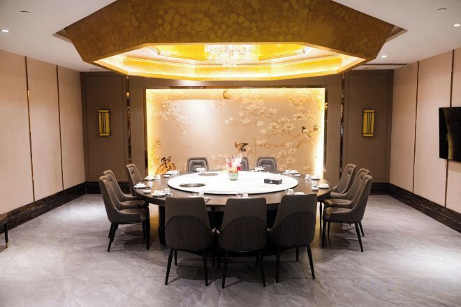 A conference room with a round table, chairs, and a decorative wall.