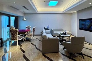 A modern hotel room with a sofa, armchairs, a dining table, and a TV. - Lijing Peninsula Hotels (Lufeng)