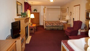 Ein Schlafzimmer mit Himmelbett, Fernseher, Schreibtisch mit Lampe und einem Sessel.