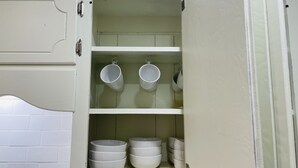 Un pensile da cucina con ciotole e tazze di ceramica bianca.