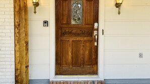 Una porta d'ingresso in legno con un vetro, due lanterne a parete e una cassetta delle lettere.