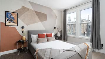 Un dormitorio moderno con una cama grande, una mesita de noche y una ventana con cortinas.
