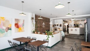 Un restaurant moderne avec un mur en briques, des tables en bois et des lampes suspendues.