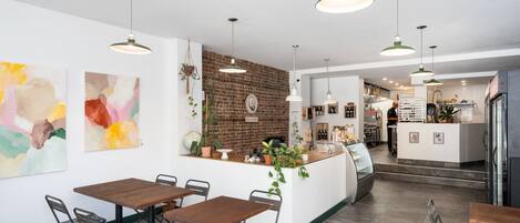 Un restaurante moderno con pared de ladrillo, mesas de madera y lámparas colgantes.