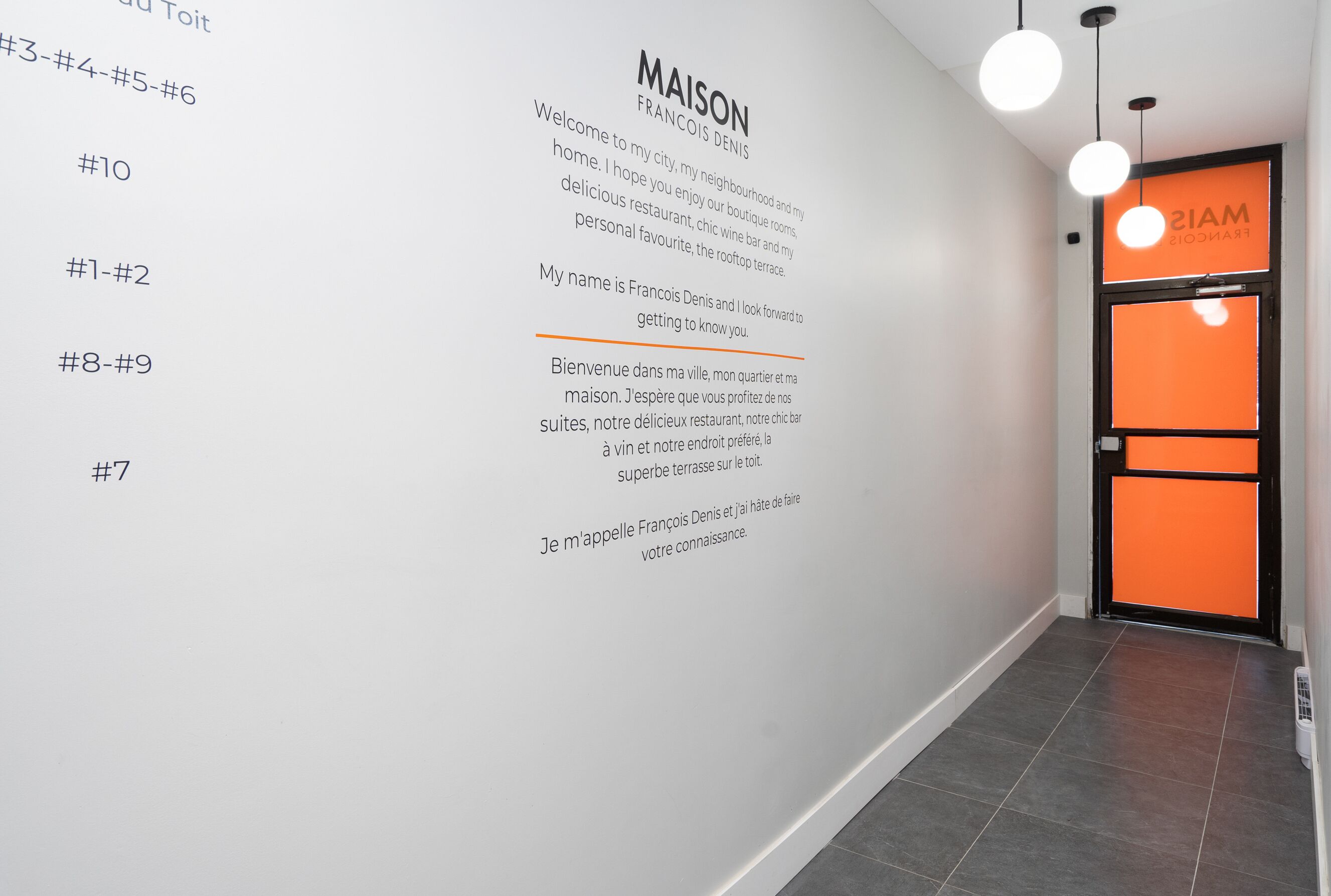 A hotel corridor with a welcome message in both English and French, a numbered list on the left, and an orange sign on the right.
