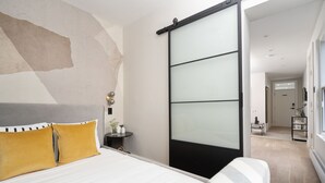 Une chambre moderne avec un lit, une porte coulissante et une vue sur une autre pièce.