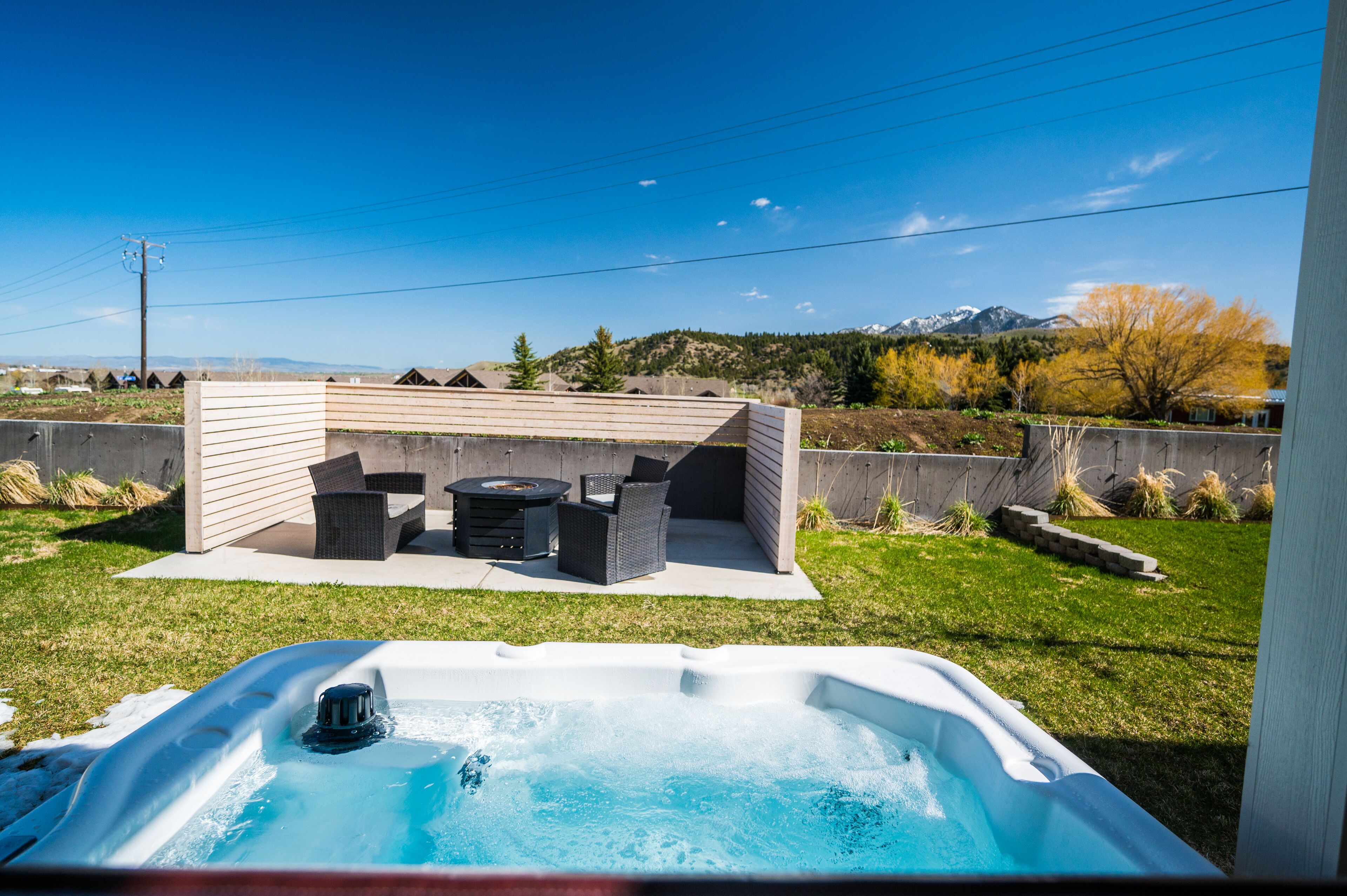 A backyard with a hot tub, outdoor furniture, and a view of mountains.