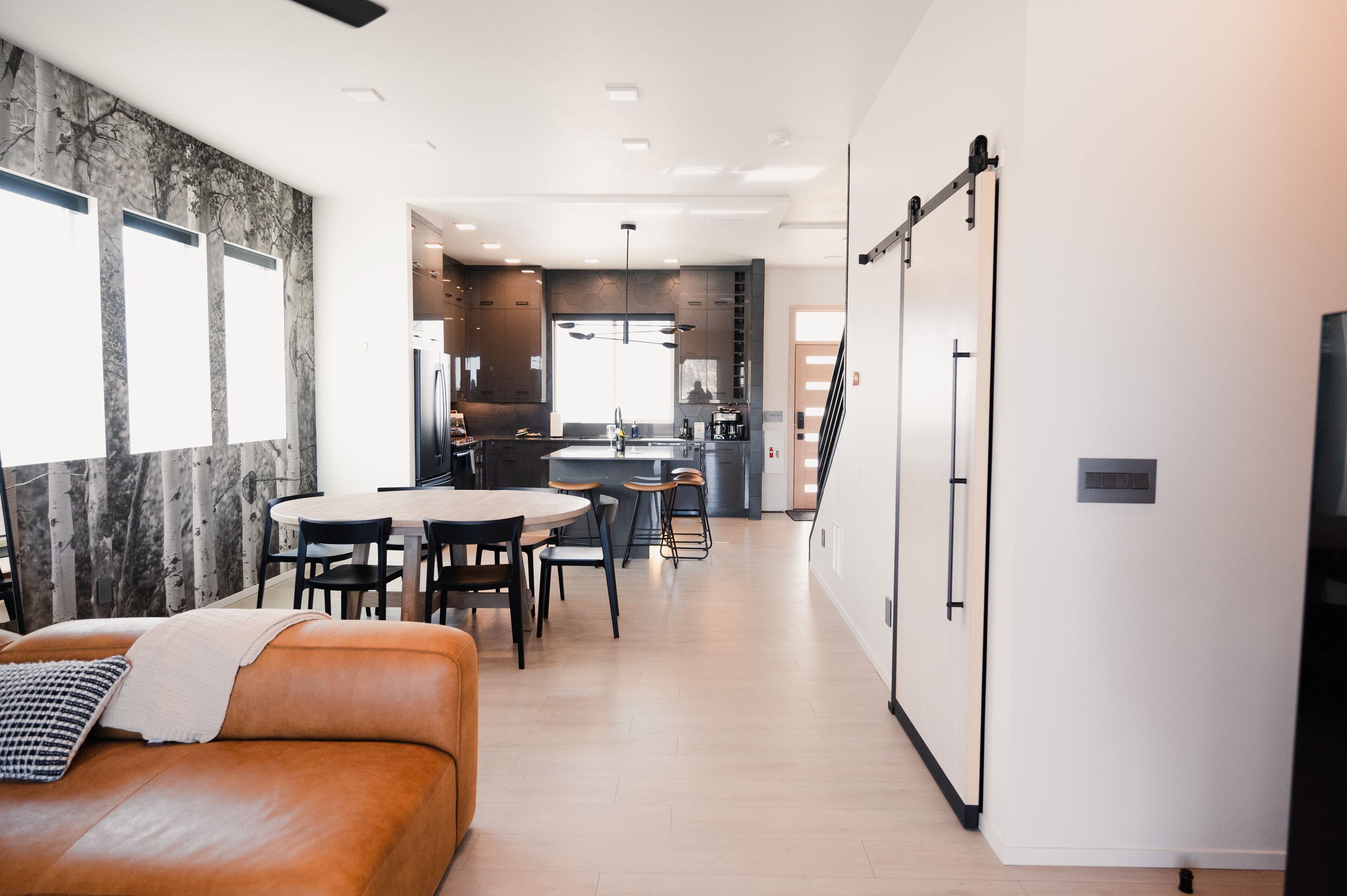 Une cuisine moderne dotée d’un îlot central, un coin repas avec une table ronde et des chaises, et un espace de vie avec un canapé et un téléviseur.