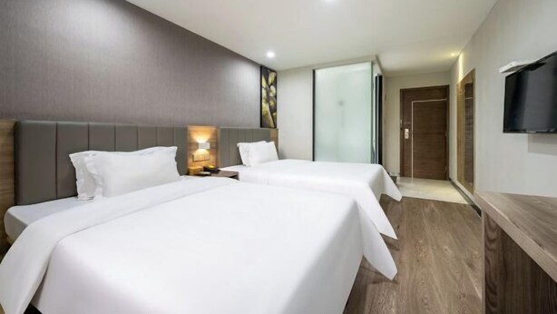 A hotel room with two beds, a flat-screen TV, and a wooden floor. - Xiyue Hotel (Dongguan Chang'an Vanke Plaza Branch) (Dongguan)