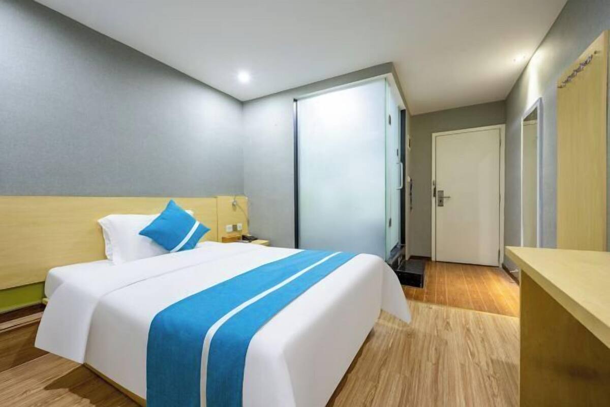 A hotel room with a bed, a nightstand, a wardrobe, and a desk.