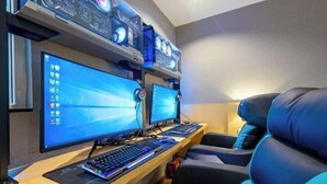 A gaming setup with two monitors, a keyboard, and a mouse on a desk, with gaming chairs and a shelf with electronic devices. - Xiyue Hotel (Dongguan Chang'an Vanke Plaza Branch) (Dongguan)