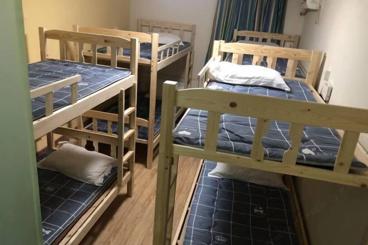 A room with bunk beds, wooden headboards, and a curtain.