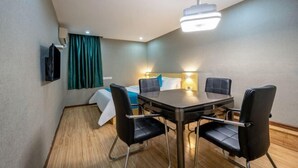 A hotel room with a dining area, a bed with a headboard, a flat-screen TV mounted on the wall, and a window with curtains. - Xiyue Hotel (Dongguan Chang'an Vanke Plaza Branch) (Dongguan)