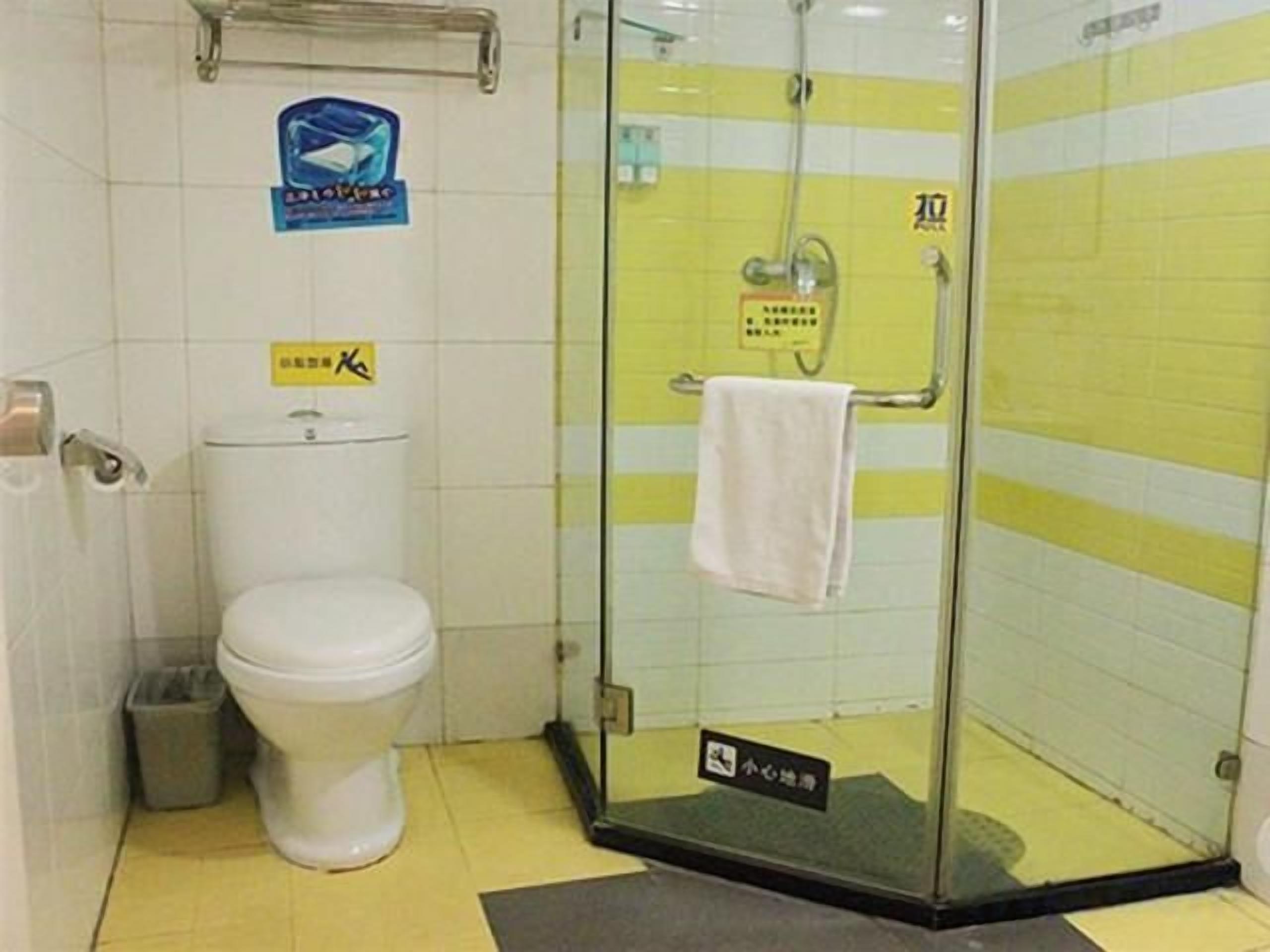 A bathroom with a toilet, a glass shower enclosure, and a towel rack.