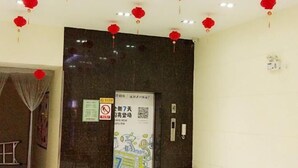 A hotel lobby with a dark marble reception desk, red lanterns hanging from the ceiling, and a poster advertising a new event. - Xiyue Hotel (Dongguan Chang'an Vanke Plaza Branch) (Dongguan)