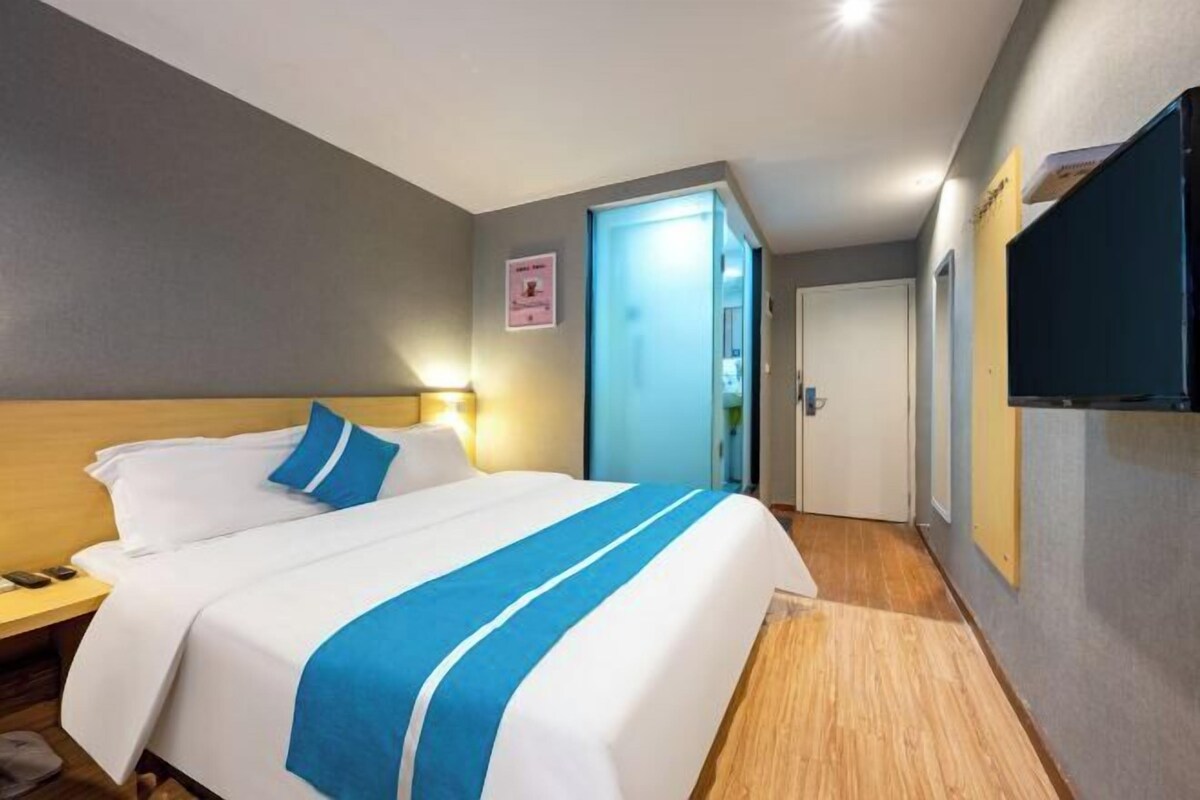 A hotel room with a bed, bedside table, and a door leading to another room.