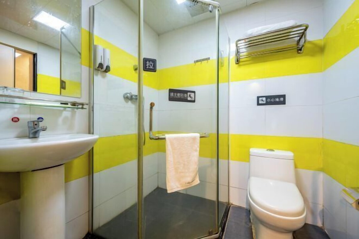 A bathroom with a glass shower enclosure, a sink, and a toilet.