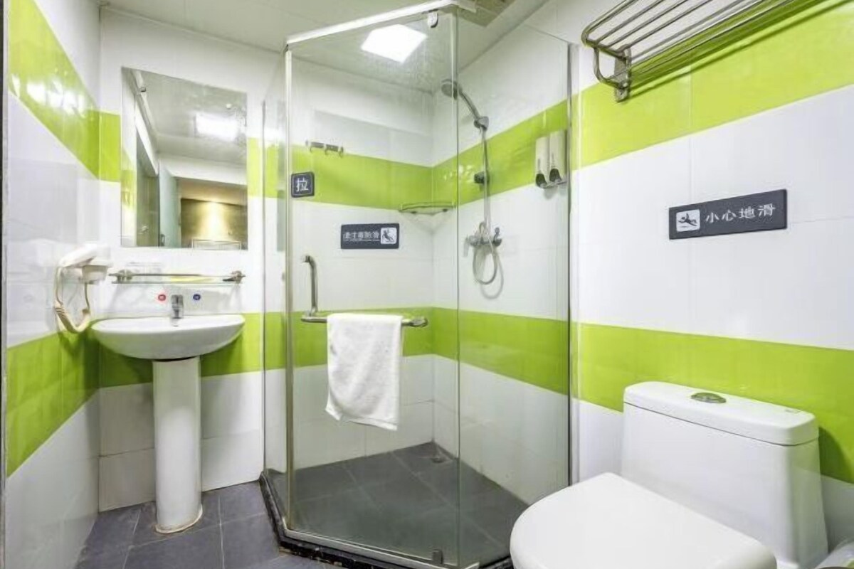 A small bathroom with a glass shower enclosure, a sink, and a toilet.