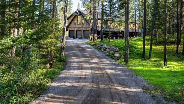A gravel road leading to a wooden cabin surrounded by trees.