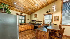 A kitchen with wooden cabinets, a refrigerator, a stove, and a sink.