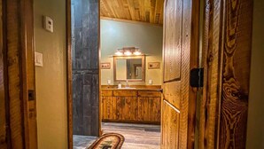 A hallway leading to a bathroom with wooden walls and a mirror above the sink.
