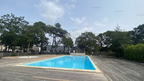 A rectangular swimming pool with a wooden deck surrounding it. - Combrit, nice duplex with heated pool, tennis court and beach on foot (COMBRIT)