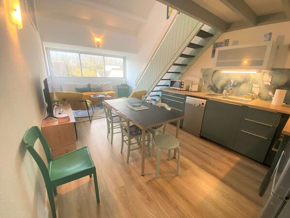 A compact kitchen with a dining area, a staircase, and a view of the outdoors.