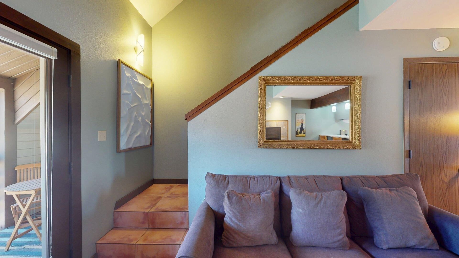 A staircase leading to a room with a couch and a large mirror.